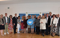 Das Foto zeigt Gesundheitsministerin Judith Gerlach, die mit dem "Weißen Engel" ausgezeichneten Geehrten und Regierungspräsident Rainer Haselbeck zusammen mit weiteren Ehrengästen.  