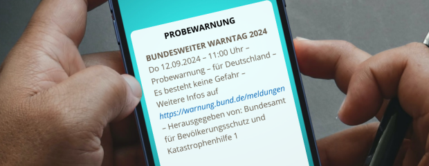 Das Foto zeigt ein Handy mit der Aufschrift "Probewarnung"